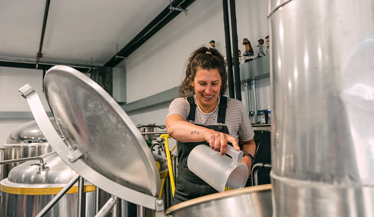Brewer pours hop pellets into a fermenter