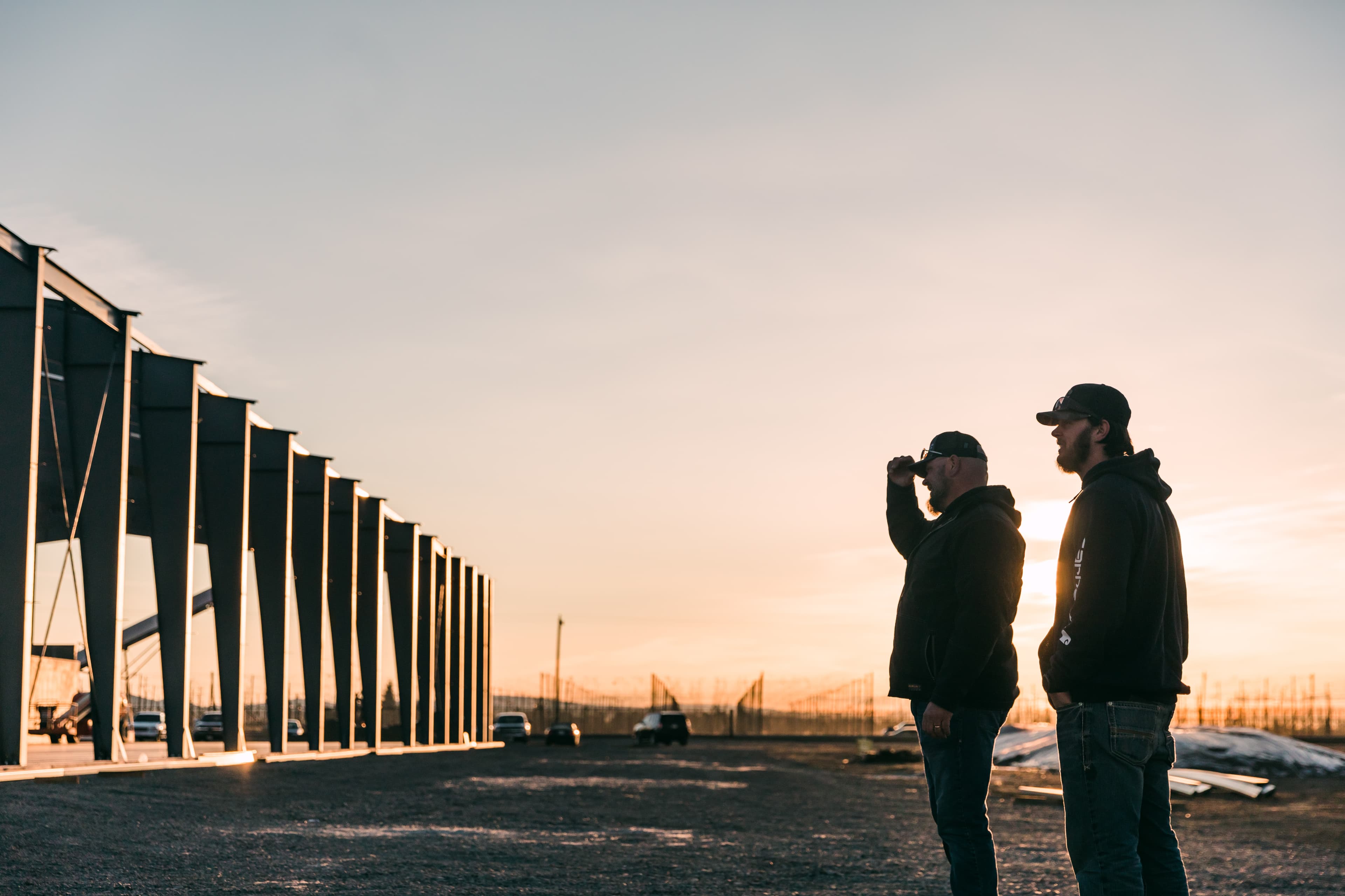 Two farmers standing outside of new facility under construction